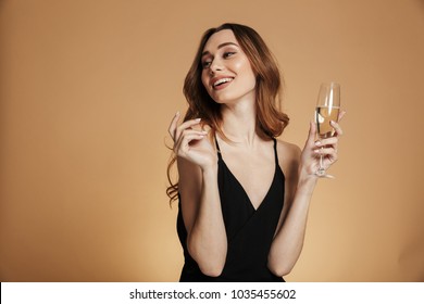 Young happy woman in black dress looking away and smiling with champagne isolated