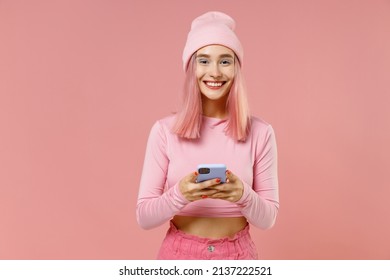 Young happy woman with bright dyed rose hair in rosy top shirt hat hold in hand use mobile cell phone isolated on plain light pastel pink background studio portrait. People lifestyle fashion concept. - Powered by Shutterstock