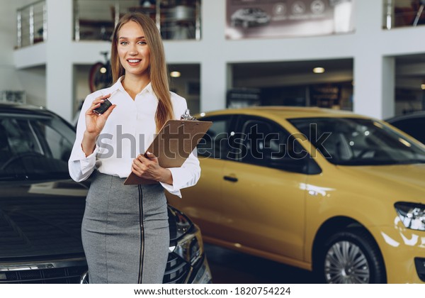 Young happy woman buyer/seller near the car with\
keys in hand