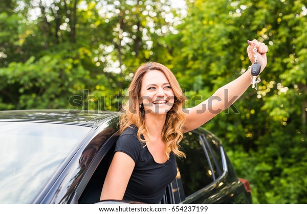 Young happy woman in the car with keys in hand -\
concept of buying car.