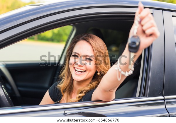 Young happy woman in the car with keys in hand -\
concept of buying car.
