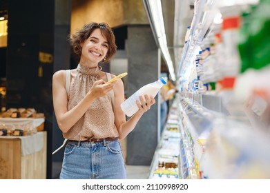 Young happy woman in casual clothes backpack shopping at supermaket store buy dairy produce take milk take photo by mobile cell phone of ingredients inside hypermarket Purchase gastronomy food concept - Powered by Shutterstock