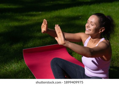 Young happy woman with closed eyes taking sunbathing and enjoying yoga oudoor in a sunny summer day
