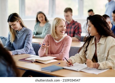 Young happy woman communicating with her female classmate during a class at the university. - Shutterstock ID 2109334547