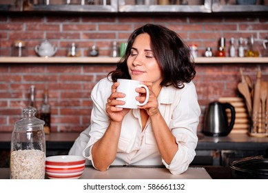 Young Happy Woman Drinking Coffee On The Kitchen In The Morning