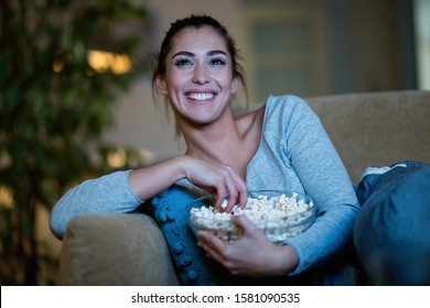 Young Happy Woman Eating Popcorn While Enjoying In Movie Night At Home. 