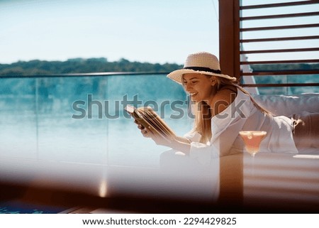 Young happy woman enjoying in reading a book by the pool during summer day. Copy space.