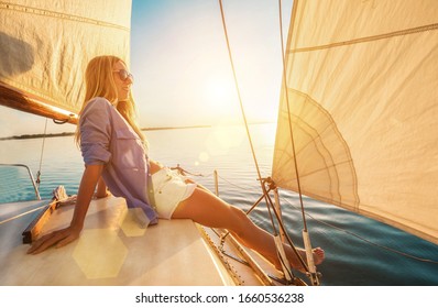 Young Happy Woman Enjoying Sunset From Deck Of Sailing Boat Moving In Sea At Evening Time. Travel, Summer, Holidays, Journey, Trip, Lifestyle, Yachting Concept.