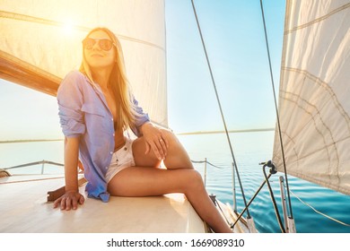 Young Happy Woman Enjoying Sunset From Deck Of Sailing Boat Moving In Sea At Evening Time. Travel, Summer, Holidays, Journey, Trip, Lifestyle, Yachting Concept.