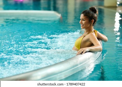 Young happy woman enjoying in thermal pool at wellness center. 