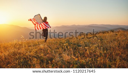 young happy woman with flag of united states enjoying the sunset on nature
