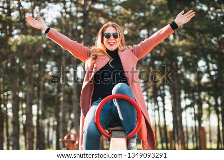 Young happy woman having fun on the seesaw in the playground