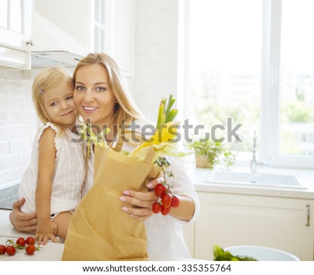 Young happy woman with her daughter cooking in a modern kitchen setting