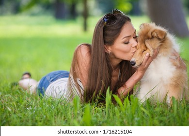 Young Happy Woman With Her Dog In Park. Kissing And Love