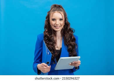 Young, Happy Woman Holding Colorful Binders, Isolated On Blue Background With Tablet In Hand. School Teacher, Principal, Student.