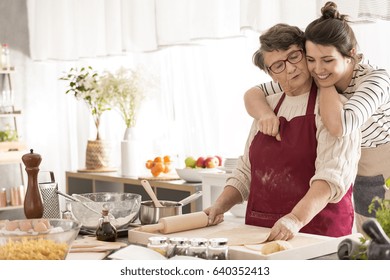 Young happy woman hugging her grandma cooking in a kitchen