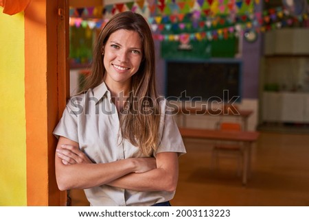 Young happy woman as a kindergarten teacher or kindergarten teacher with crossed arms
