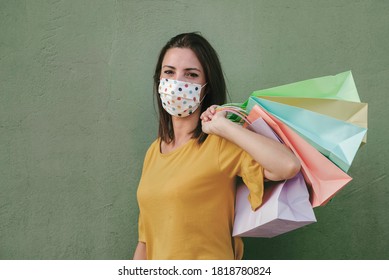 Young Happy Woman With Medical Mask Holding A Shopping Bags Over Green Background