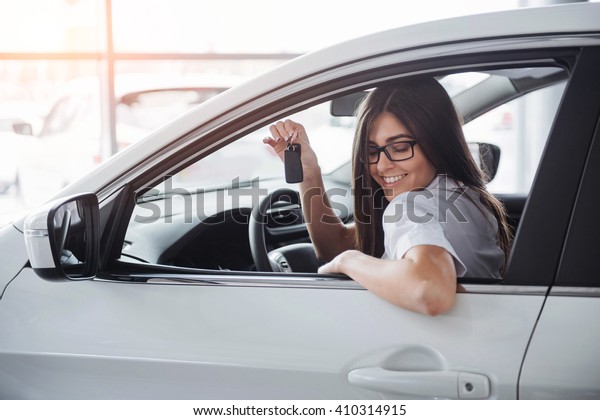 Young happy woman near the car with keys in hand -\
concept of buying car