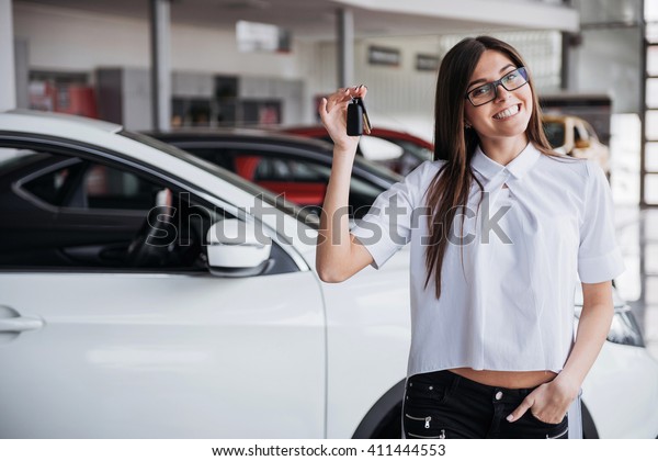 Young happy woman near the car with keys in hand -
concept of buying car