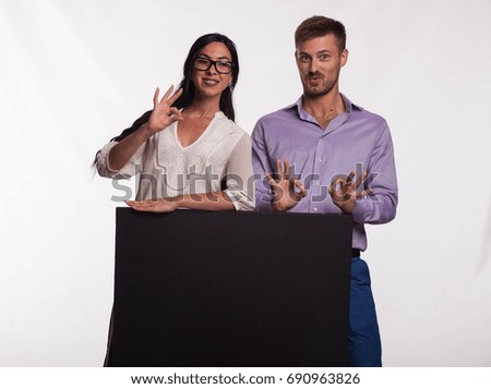 Young happy woman portrait of a confident businesswoman showing presentation, pointing placard gray background. Ideal for banners, registration forms, presentation, landings, presenting concept.