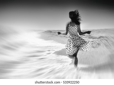 Young Happy Woman Running On The Beach Back To Camera. Black And White Photo.