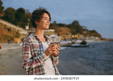 Young happy woman she wear shirt casual clothes hold takeaway delivery craft paper brown cup coffee to go rest on sea ocean sand shore beach outdoor seaside in summer day free time. Lifestyle concept - Powered by Shutterstock