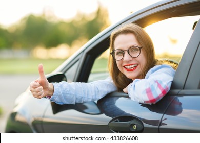 Young Happy Woman Sitting In A Car With Thumb Up - Concept Of Buying A Used Car Or A Rental Car