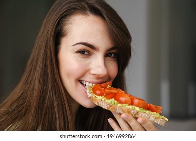 Young Happy Woman Smiling While Eating Avocado Toast Indoors