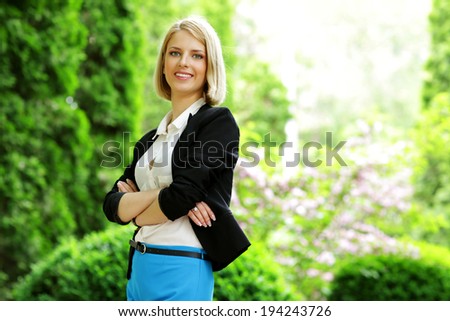 Young happy woman standing with arms folded in park