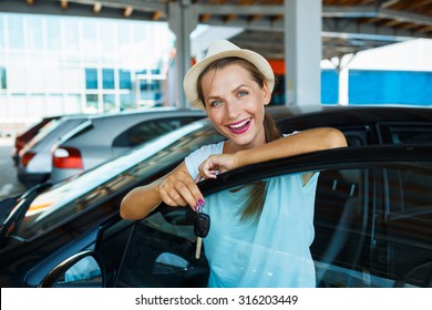 Young Happy Woman Standing Near A Car With Keys In Hand - Concept Of Buying A Used Car