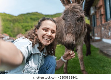 Young happy woman taking selfie with donkey at farm - Powered by Shutterstock