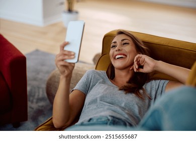 Young happy woman texting on cell phone while relaxing at home.  - Powered by Shutterstock