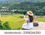 Young happy woman tourist enjoying and relaxing with beautiful landscape view rice paddy field while traveling at Nan, Thailand