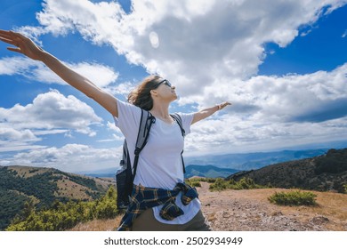 Young happy woman traveler hiker standing with outstretched arms against mountain summer landscape on top - Powered by Shutterstock