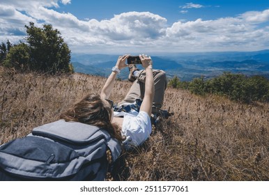 Young happy woman traveler hiker resting during hiking in summer mountains with smartphone in hands - Powered by Shutterstock