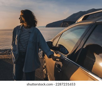 Young happy woman traveler opening car door. Sunset beach portrait - Powered by Shutterstock