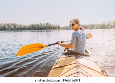 Young happy woman travels on the river. View from the back. The face is turned towards the camera. The traveler smiles.