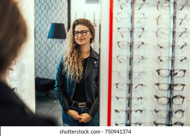 Young Happy Woman Trying Her New Pair Of Glasses, Looking On Mirror.