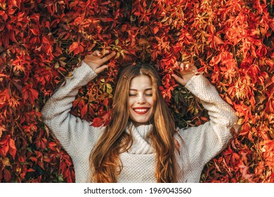 Young happy woman upon a wall of red ivy leaves. - Powered by Shutterstock