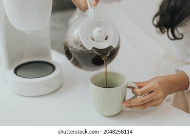 Young Happy Woman Using Coffee Maker At Home. Asian Woman Pouring Coffee In A Cup And Making Coffee At Home.