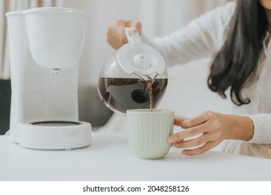 Young happy woman using coffee maker at home. Asian woman pouring coffee in a cup and making coffee at home. - Powered by Shutterstock