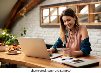 Young Happy Woman Using Credit Card And Laptop While Shopping On The Internet At Home.