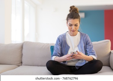 Young Happy Woman Using Mobile Phone On Sofa At Luxury Home