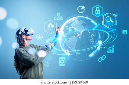 Young happy woman in vr googles working in virtual reality, earth digital hologram with icons. Metaverse and global connection. Concept of worldwide network