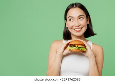 Young happy woman wear white clothes hold eat burger look aside on workspace area mockup isolated on plain pastel light green background. Proper nutrition healthy fast food unhealthy choice concept - Shutterstock ID 2271762583