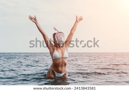 Young happy woman in white bikini and wearing pink mask gets ready for sea snorkeling. Positive smiling woman relaxing and enjoying water activities with family summer travel holidays vacation on sea.