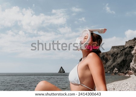 Young happy woman in white bikini and wearing pink mask gets ready for sea snorkeling. Positive smiling woman relaxing and enjoying water activities with family summer travel holidays vacation on sea.