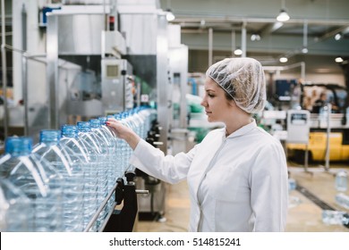 Young Happy Woman Worker In Factory Checking Water Gallons Before Shipment.