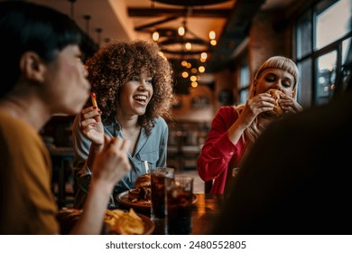 Young happy women eating burgers and talking in a pub - Powered by Shutterstock